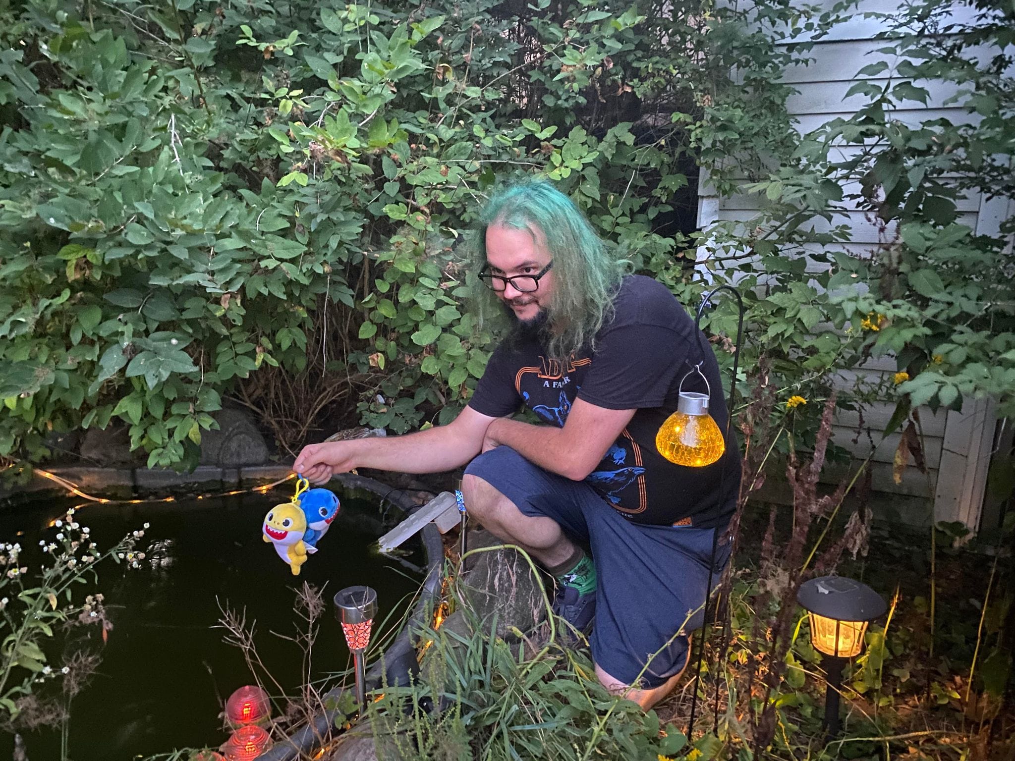 A man with green hair shows off his fish toys as though they were an impressive catch, Photo 1